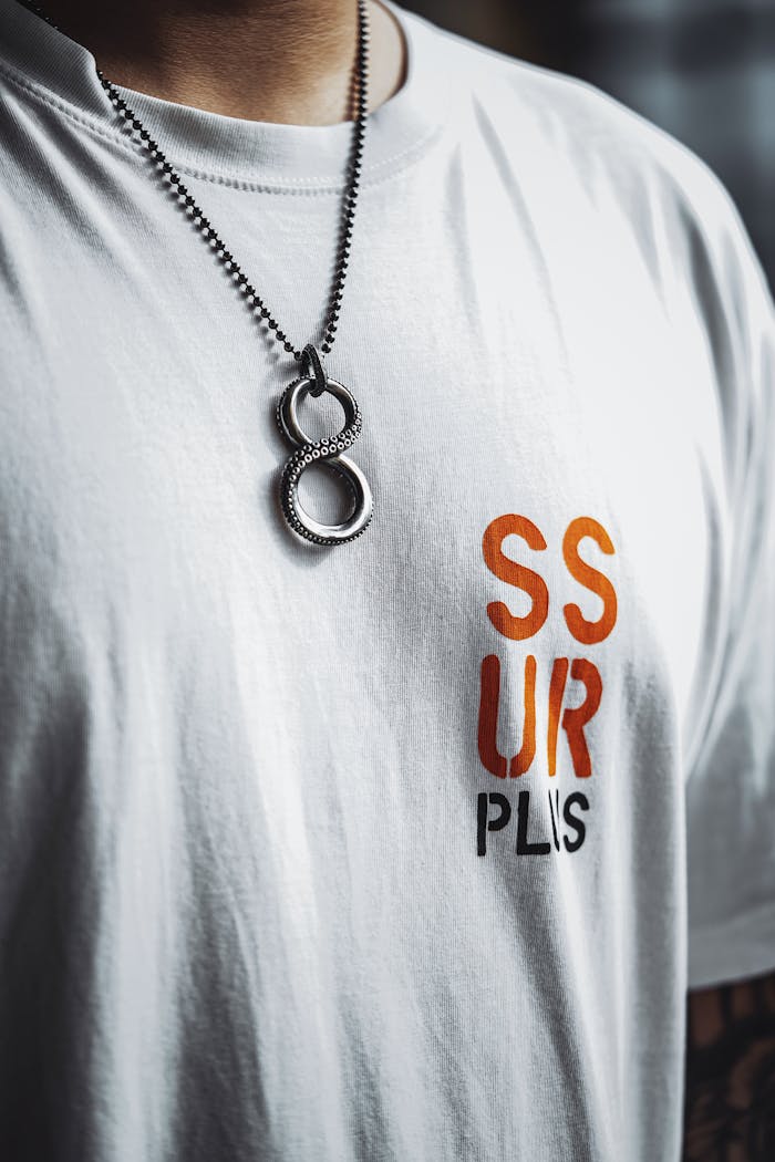 Close-up of a stylish necklace with number eight design worn over a graphic white t-shirt.